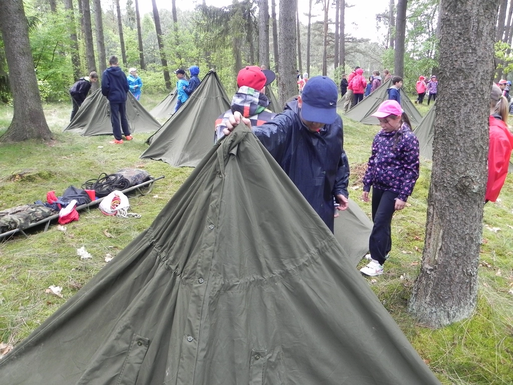dzieci sprawdzajace swoje namioty w lesie